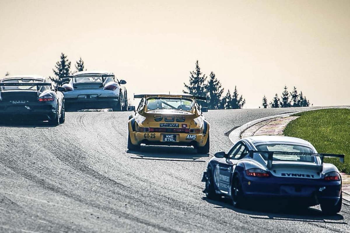 The field charges into Les Combes at the end of Kemmel Straight — a rapid right-left sequence that flows into a sweeping bend.